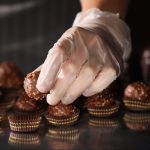 Woman packing delicious candies at production line, closeup